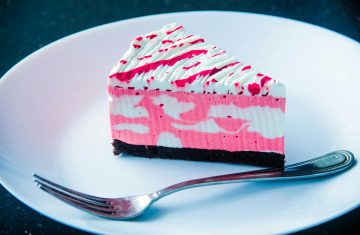 Sliced White and Pink Icing Covered Cake on White Plate With Silver-colored Fork
